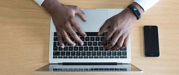 A man typing an email on a laptop.